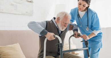 Doctor helping to retired man, getting up from sofa