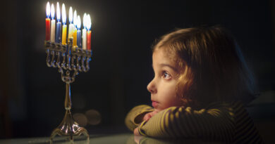 a girl starring candles of hanukah