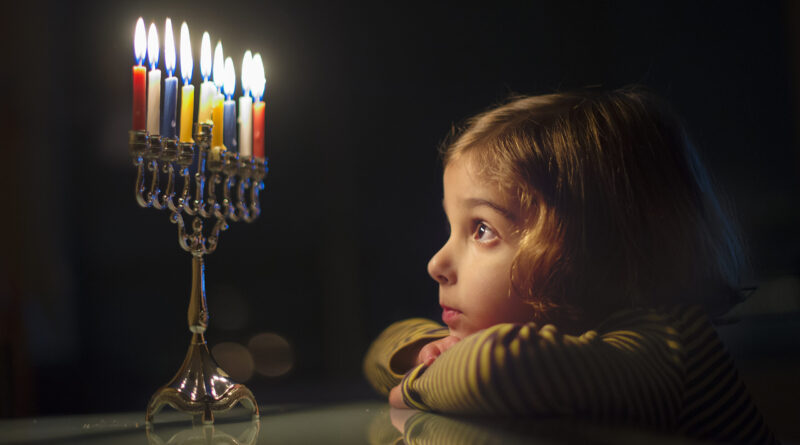 a girl starring candles of hanukah